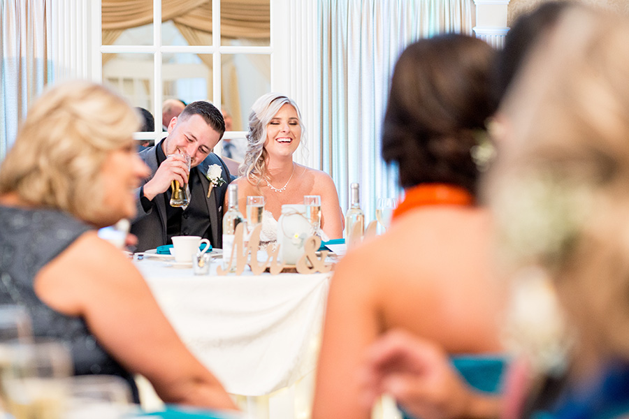 bride and groom laugh together at wedding reception