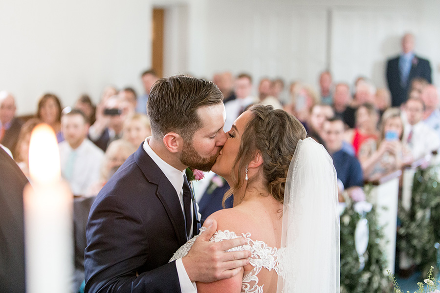bride and groom share first kiss at married couple