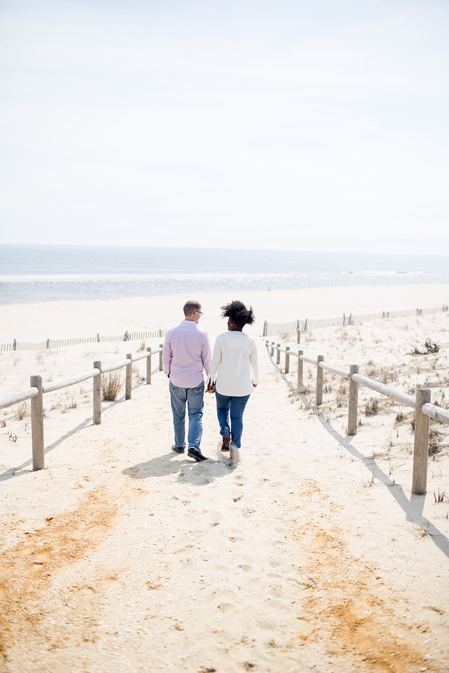 engaged couple walks on the beach in LBI