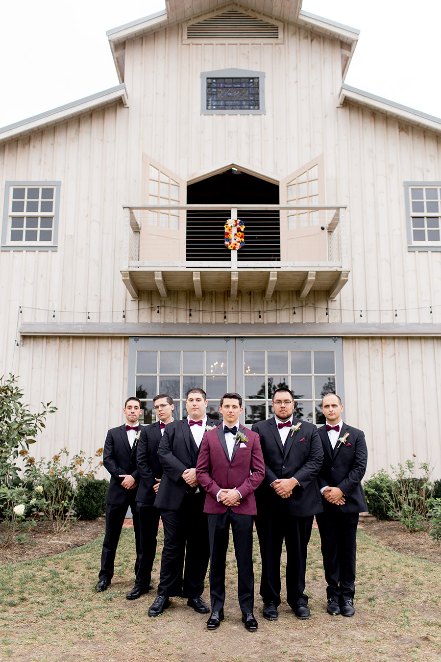 groom and his groomsmen in front of the barn