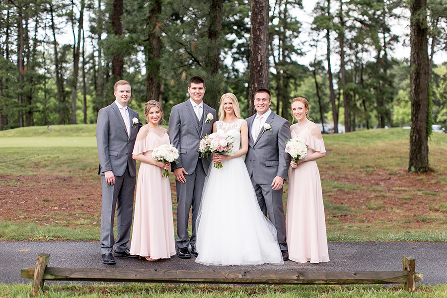 wedding party standing near the pines on the golf course
