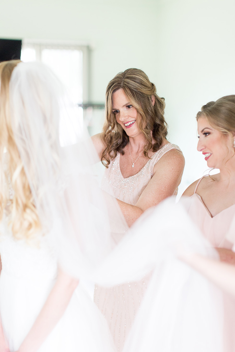 mother of bride helping bride with her dress