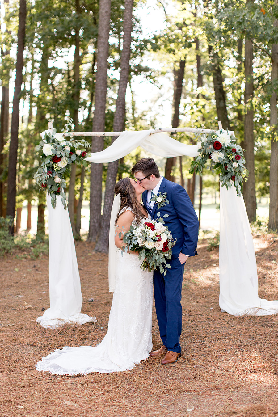 wedding couple kissing beneath their ceremony arch