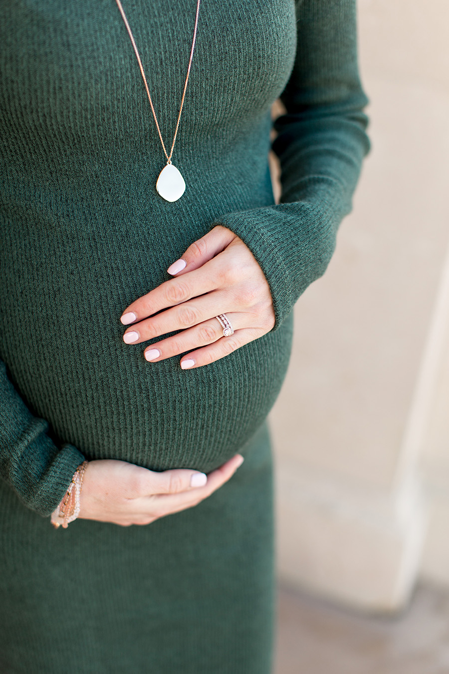 expecting mom holds her belly with wedding rings