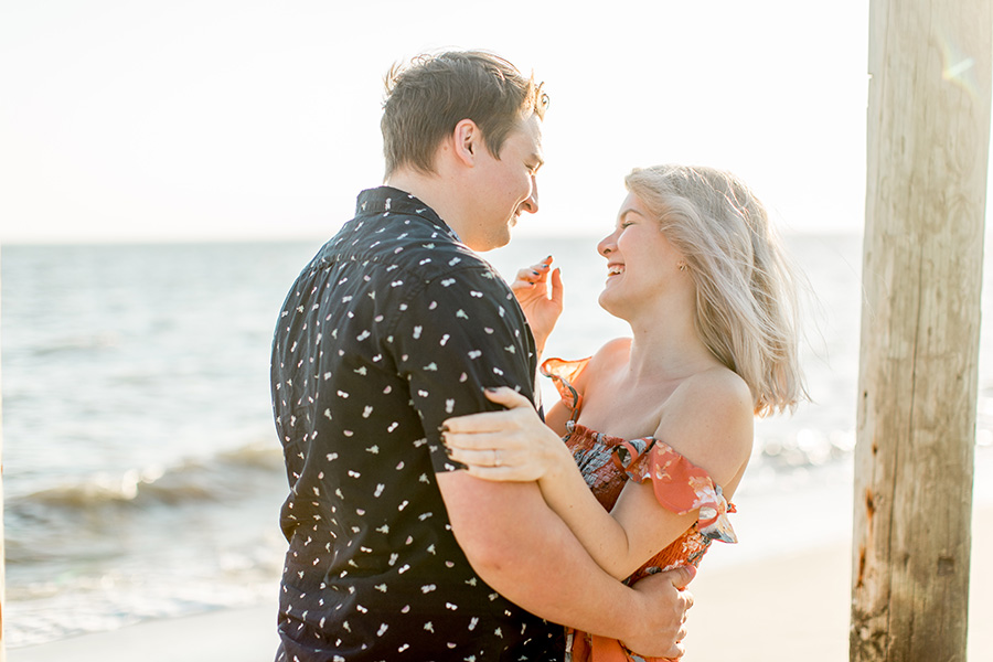 engaged couple laughing together on the beach